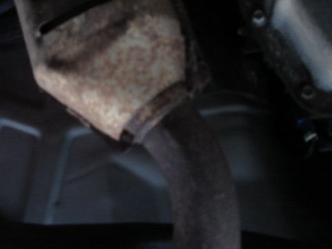 2000 Ford Crown Victoria - Underside view of a rusted catalytic converter and exhaust pipe, with Supermotors.net watermark.
