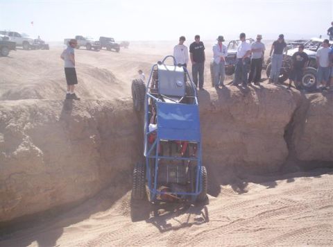 1987 Suzuki Samurai - A group of people observe an off-road buggy navigating a steep sandy dune.