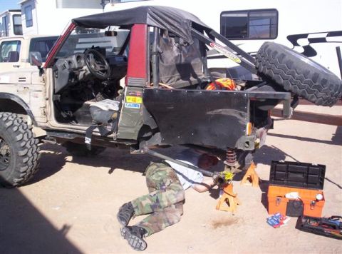 1987 Suzuki Samurai - Person works on the rear suspension of a 1987 Suzuki Samurai.