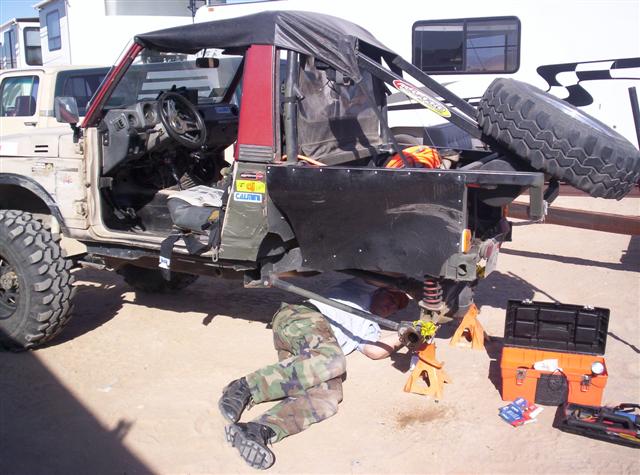 1987 Suzuki Samurai with soft top removed, being worked on by a person underneath