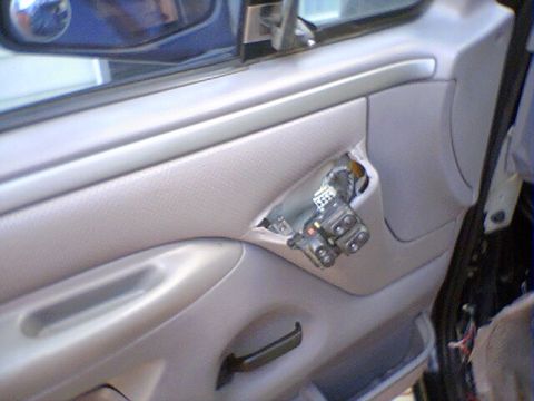 1994 Ford Bronco - Close-up of a car's interior door panel, showing exposed wiring and window control mechanisms.