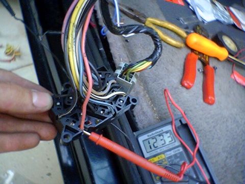 1994 Ford Bronco - A technician tests voltage on a complex automotive wiring harness using a multimeter.