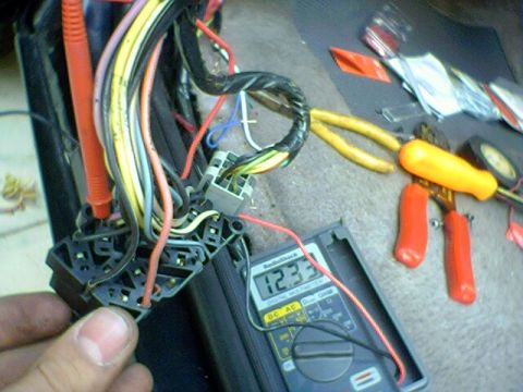 1994 Ford Bronco - A multimeter displays 12.33 volts while testing a vehicle's wiring harness, with tools nearby.
