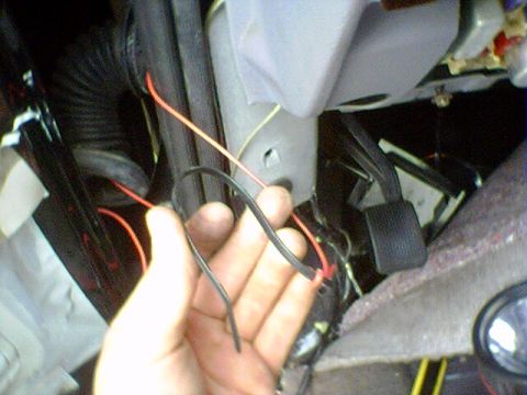 1994 Ford Bronco - Close-up of vehicle interior wiring and pedals, with a hand holding loose wires.
