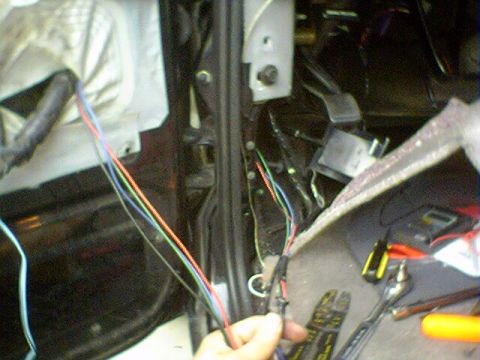 1994 Ford Bronco - Close-up of a vehicle's interior wiring harness, showing multiple colored wires and tools nearby.