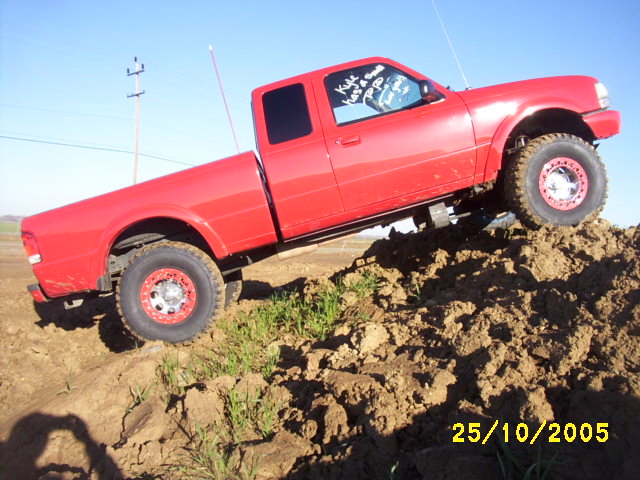 Red pickup truck climbing a dirt mound. Text on the driver's side window says 'Kyle has a good popo'