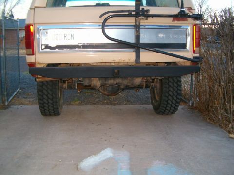 1985 Ford Bronco - The rear of a tan truck is shown, a bike rack and a license plate.