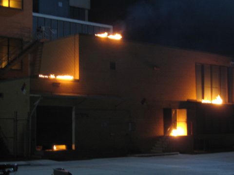 1990 Ford Bronco - multi-level building burns at night with flames erupting from windows, a doorway and the rooftop.