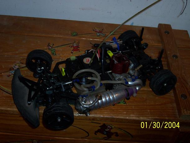 RC car with red engine and silver exhaust pipe on a wooden surface