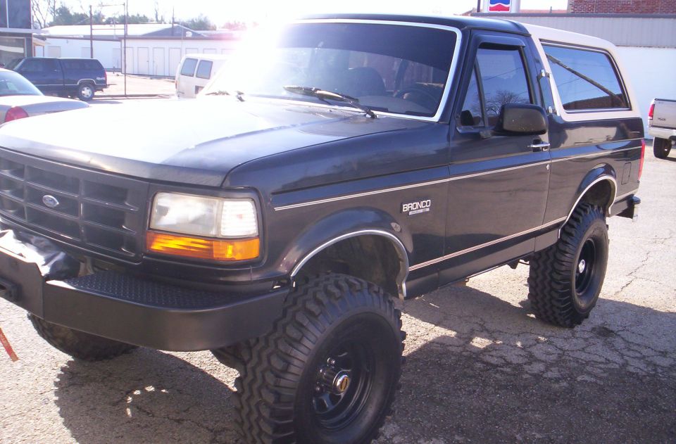 Dark blue Ford Bronco with lifted suspension and large tires