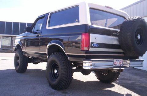 1993 Ford Bronco - This lifted Ford Bronco features a two-tone black and tan paint scheme with a spare tire mounted on the rear.