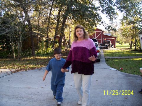 1987 Ford Bronco - A woman and child walk on a driveway in front of a red barn, with two vehicles visible in the background.