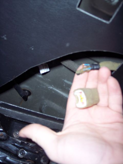 1995 Ford Probe - A hand holds a disconnected power antenna connector, revealing exposed wires and the internal yellow and white components.