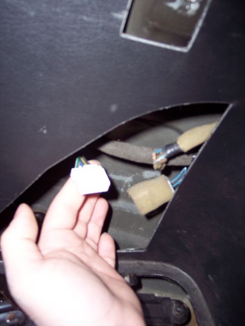 1995 Ford Probe - A hand holds a wiring connector, revealing exposed wires and foam padding within a car's interior panel.