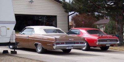 1972 Ford Ranchero - Two vintage cars are parked in a driveway next to a garage, with a trailer on the left.
