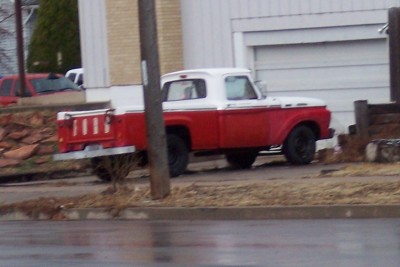 1972 Ford Ranchero - A two-tone red and white pickup truck is parked in front of a garage.