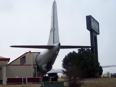 1972 Ford Ranchero - The rear of an airplane is integrated into a building, with a hotel sign in the background.