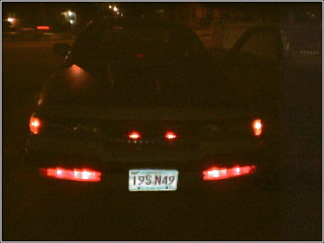 Rear view of a sedan at night with taillights lit and license plate 19S N49