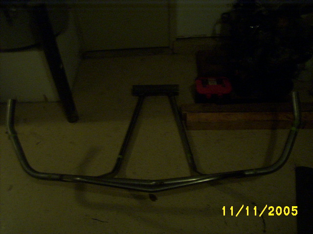 Welded tubular steel bumper on garage floor at night, dim lighting