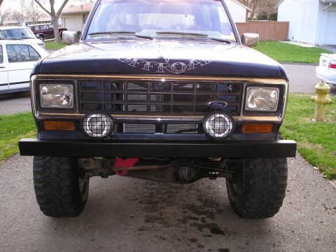 1986 Ford Bronco II - The front of a 1986 Ford Bronco II is shown, a black aftermarket bumper and auxiliary lights mounted below the grille.