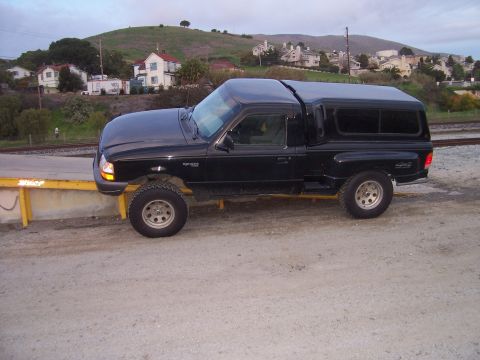 1998 Ford Ranger - This black 1998 Ford Ranger pickup truck is shown from the side, equipped with a camper shell.