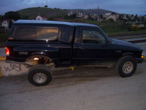 1998 Ford Ranger - This black 1998 Ford Ranger pickup truck is equipped with a camper shell and off-road tires.