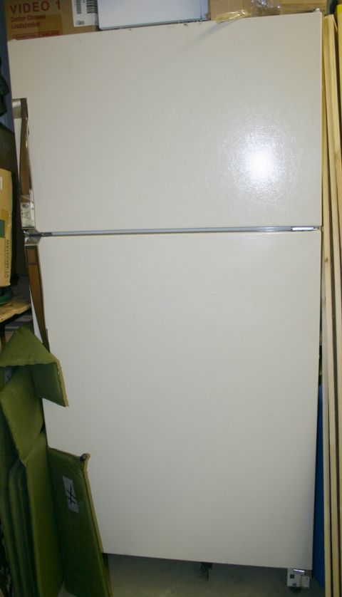 2003 Jeep TJ - A white refrigerator with a top freezer is shown in a cluttered room with boxes and cushions.