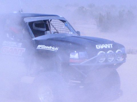 Dark off-road race truck with triple lights and GIANT sponsor decal in dust