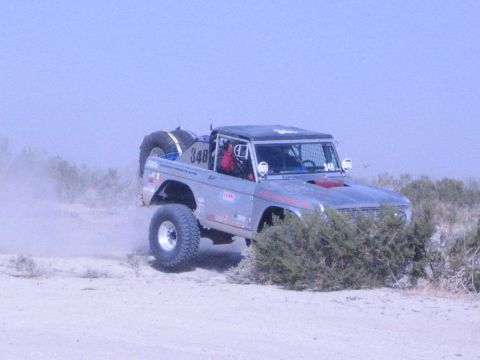 Silver number 348 off-road race truck with spare tire, front wheels airborne