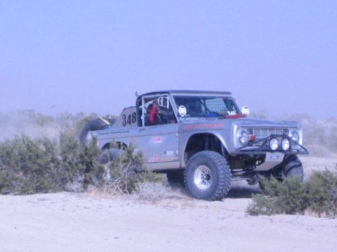 Silver number 348 off-road race truck on big tires on desert trail