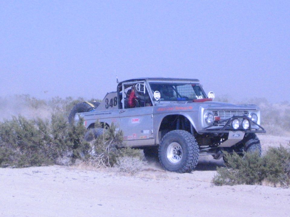 Silver number 348 off-road race truck on big tires on desert trail