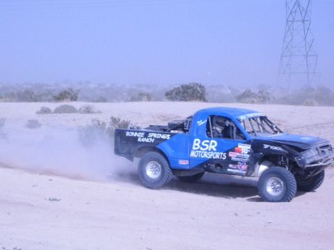 Blue BSR Motorsports off-road race truck speeding past power lines in desert