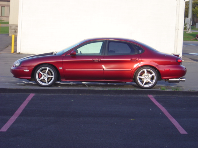 Red 1998 Ford Taurus sedan, side view, with aftermarket wheels and spoiler