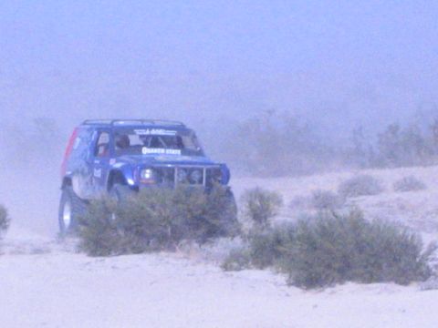 Blue off-road race SUV with Quaker State decal on dusty desert sand