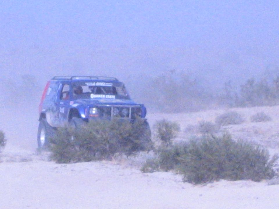 Blue off-road race SUV with Quaker State decal on dusty desert sand