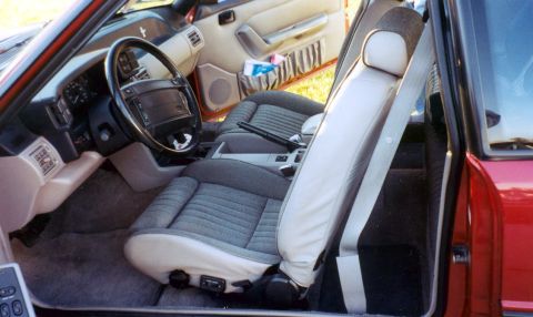 1991 Ford Bronco - The interior of a red car is visible, cloth seats and a dashboard with a steering wheel.