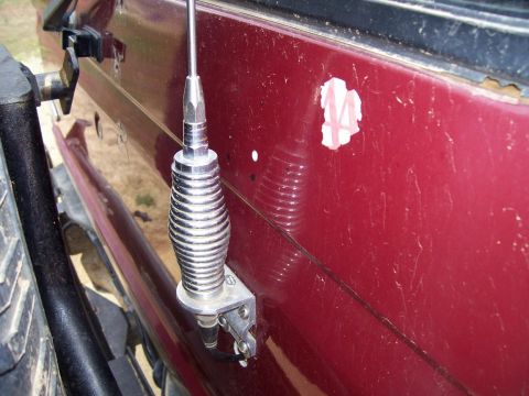 1989 Ford Bronco II - A close-up shot focuses on a CB antenna attached to the side panel of a red vehicle.