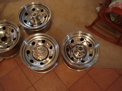 2000 Ford Crown Victoria - A set of four chrome wheels are displayed on a tiled floor, with a rocking chair visible in the background.