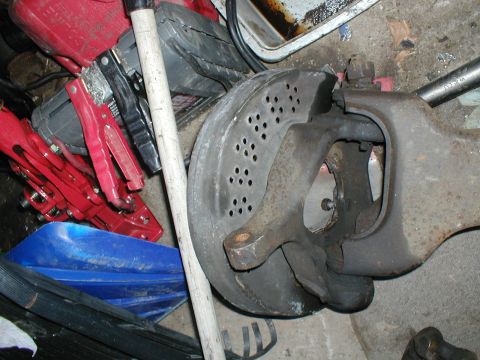 1979 Ford Bronco - A close-up view of a vehicle's brake rotor and suspension assembly, with various tools in the background.