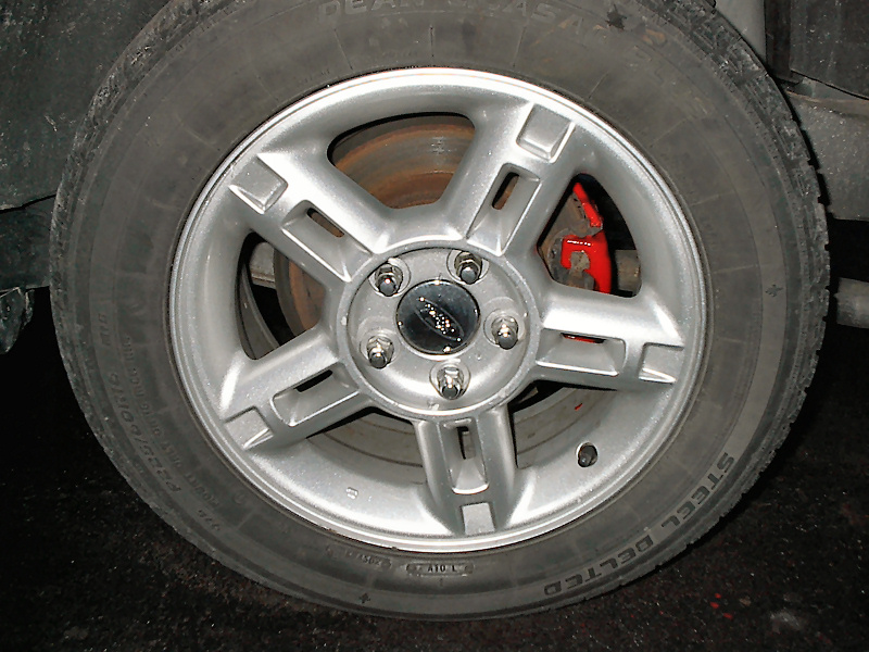Close-up of a silver 5-spoke wheel with a red brake caliper visible behind it