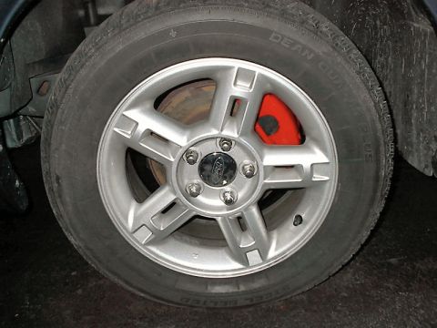 1985 Mercury Grand Marquis - This image shows a close-up of a vehicle's wheel and tire, highlighting a red brake caliper behind the spokes.