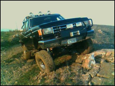 1988 Ford Bronco - This black 1988 Ford Bronco navigates a challenging rocky trail, its off-road capabilities.