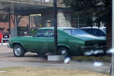 1972 Ford Ranchero - A green coupe is parked under an awning at a service station, with another vehicle visible behind it.
