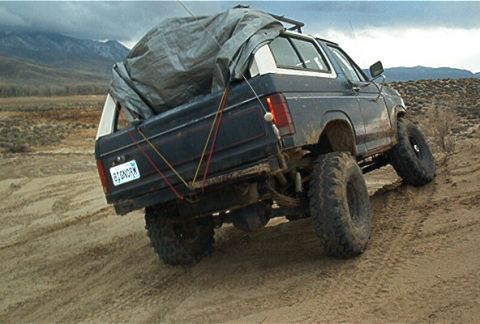 1986 Ford Bronco - This modified SUV is equipped for off-road use, with large tires and a tarped load in the rear.