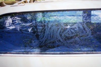 1972 Ford Ranchero - Rear window of a car features custom etched artwork depicting a landscape and abstract designs.
