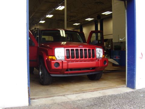 1997 Ford Taurus - A red Jeep Commander is parked inside a garage with its doors open. The vehicle's front grille and headlights are clearly visible.