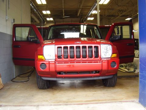 1997 Ford Taurus - Front view of a red Jeep Commander SUV with all doors open, parked inside a garage or workshop.