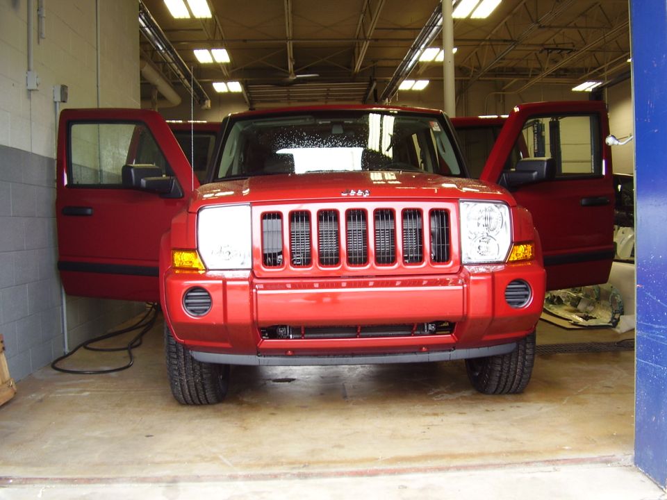 Red Jeep Commander with doors open, parked indoors