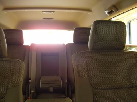 1997 Ford Taurus - The interior of a vehicle shows multiple rows of fabric seats and headrests, with bright light filtering through the rear window.