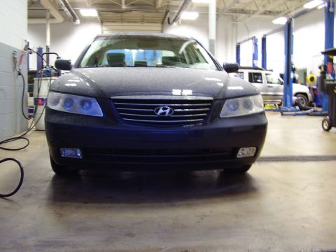 1997 Ford Taurus - Front view of a dark colored Hyundai Grandeur parked inside a service bay.